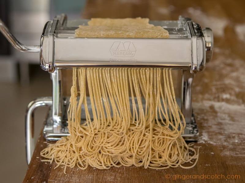 Cutting the noodle dough with the spaghettini-sized cutter to make homemade Chinese egg noodles from scratch
